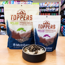 two bags of new Mud Bay food toppers and a bowl with toppers over food